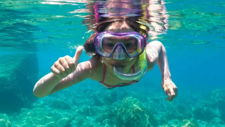 Snorkeler swimming above scuba divers over coral reef in Varadero Cuba